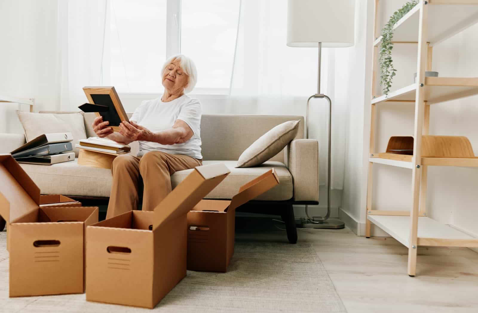 A senior packs boxes with photos, preparing for their move to Memory Care.